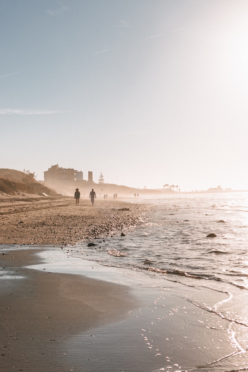 A sandy beach with people walking on it